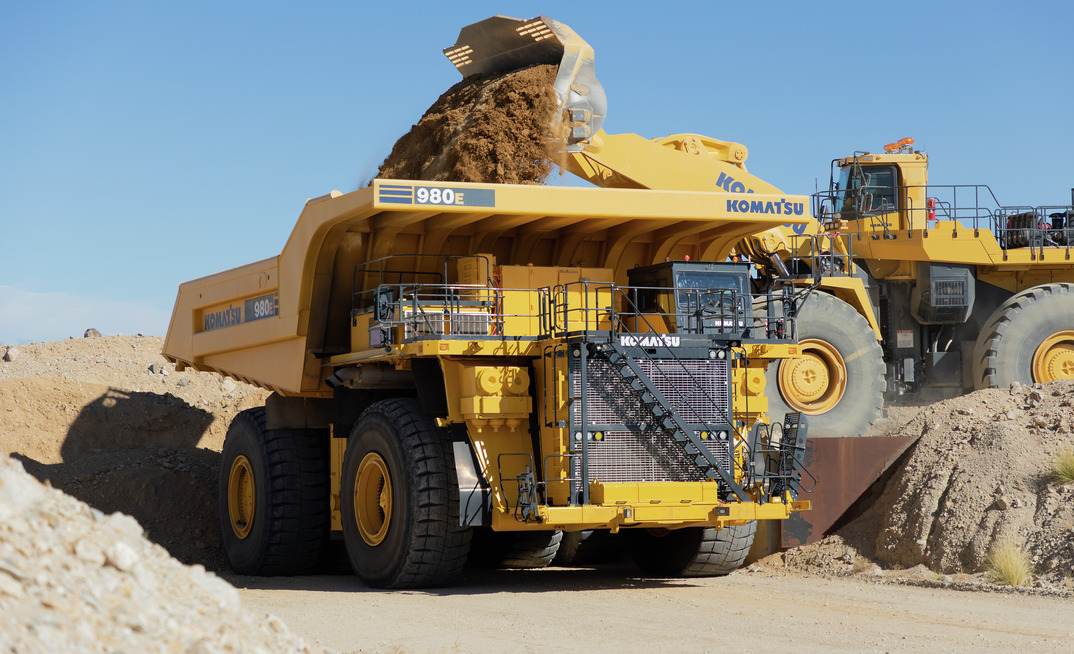 A Komatsu 980E haul truck being loaded by a wheel loader