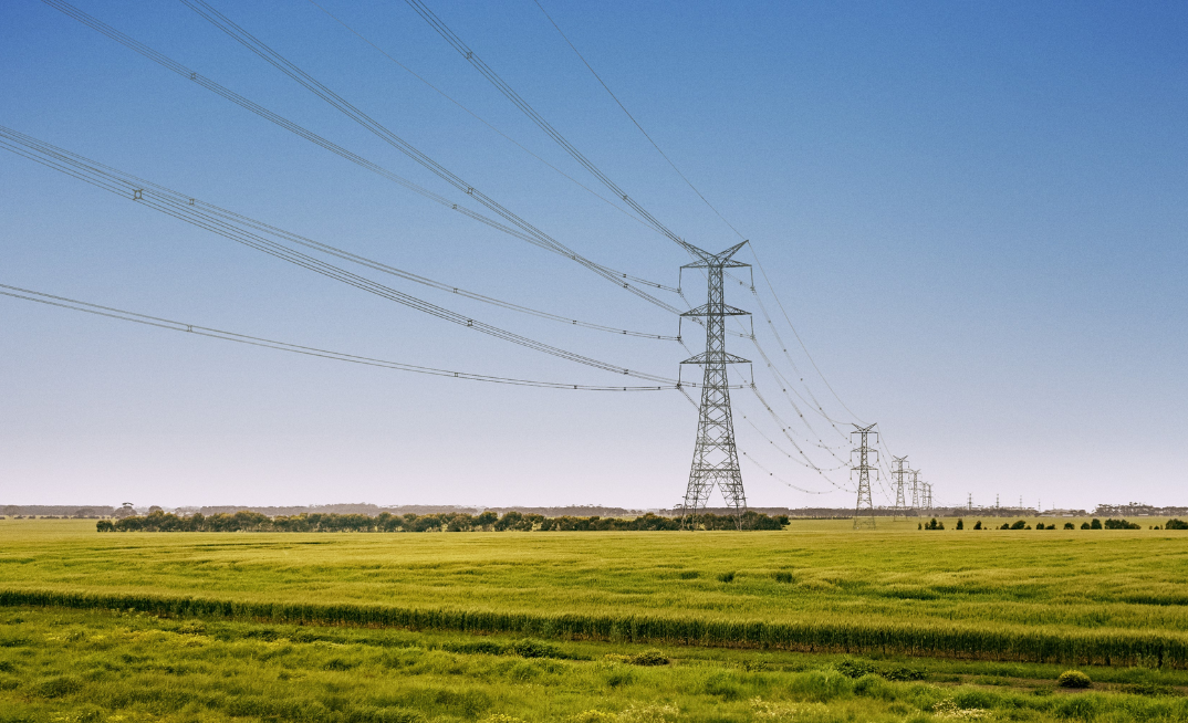 Large electricity transmission towers running across a field
