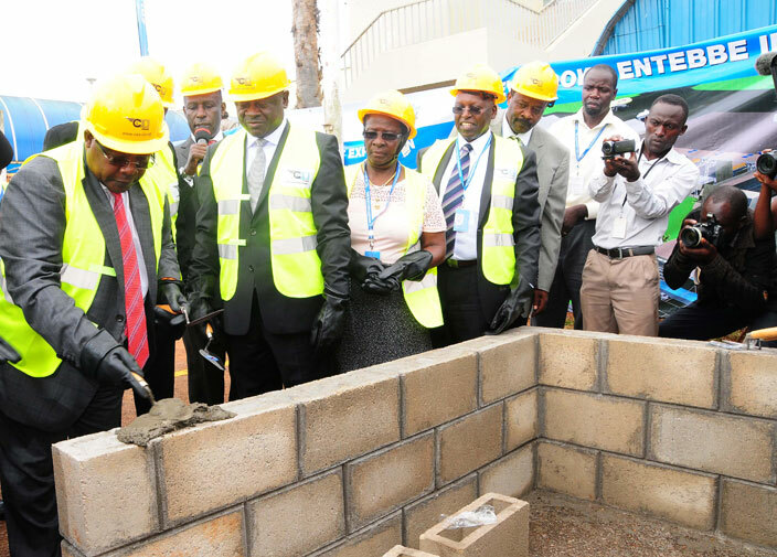  yabagambi lays a brick on the foundation of the airports terminal expansion building as  board members look on