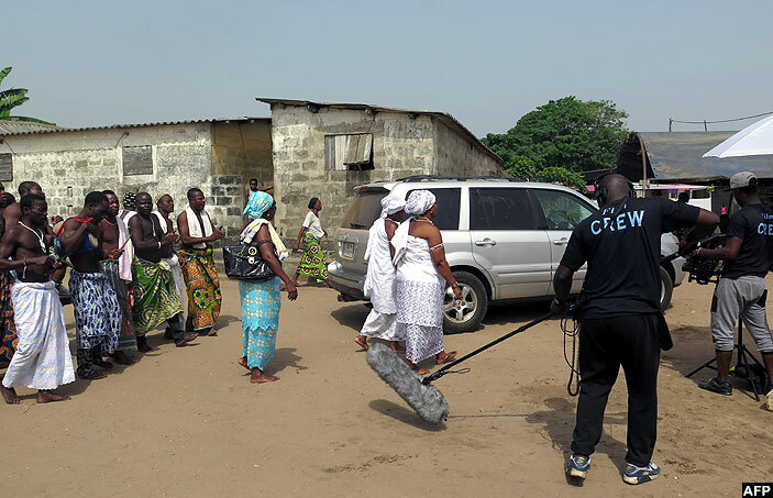   film crew following voodoo worshippers dressed in white robes and walking barefoot in a procession