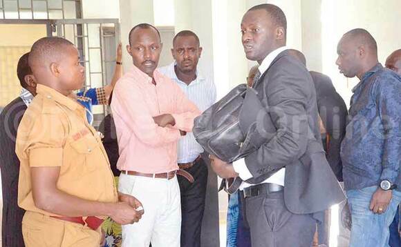 Omu ku basibe Abanyarwanda (mu ppinki) bwe yali ayogerako ne munnamateeka we Eron Kiiza mu kkooti y'amagye e Makindye. Omu ku basibe Abanyarwanda (mu ppinki) bwe yali ayogerako ne munnamateeka we Eron Kiiza mu kkooti y'amagye e Makindye.
