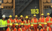 A group of women miners stand in front of large truck. 