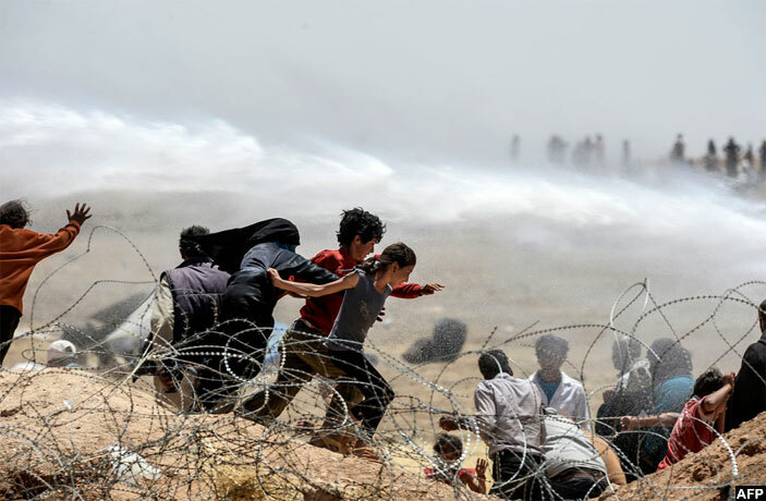  urkish soldiers use water cannon to move yrian refugees from border fences at kcakale in anliurfa province on une 13 2015