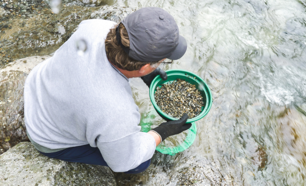 A man uses a sieve to fossick in a body of water